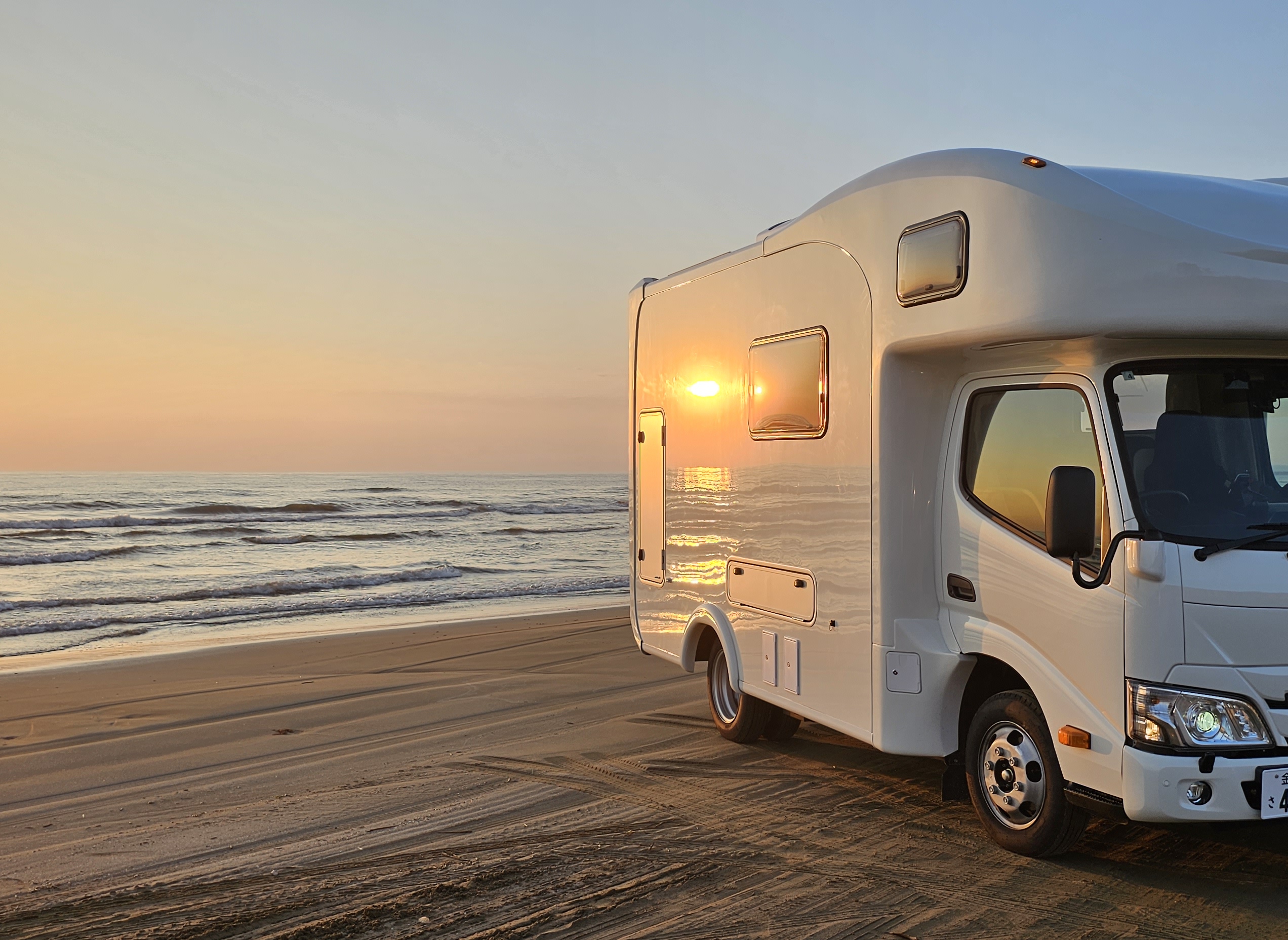 夕暮れの海辺に停まるeight caravanのキャンピングカー